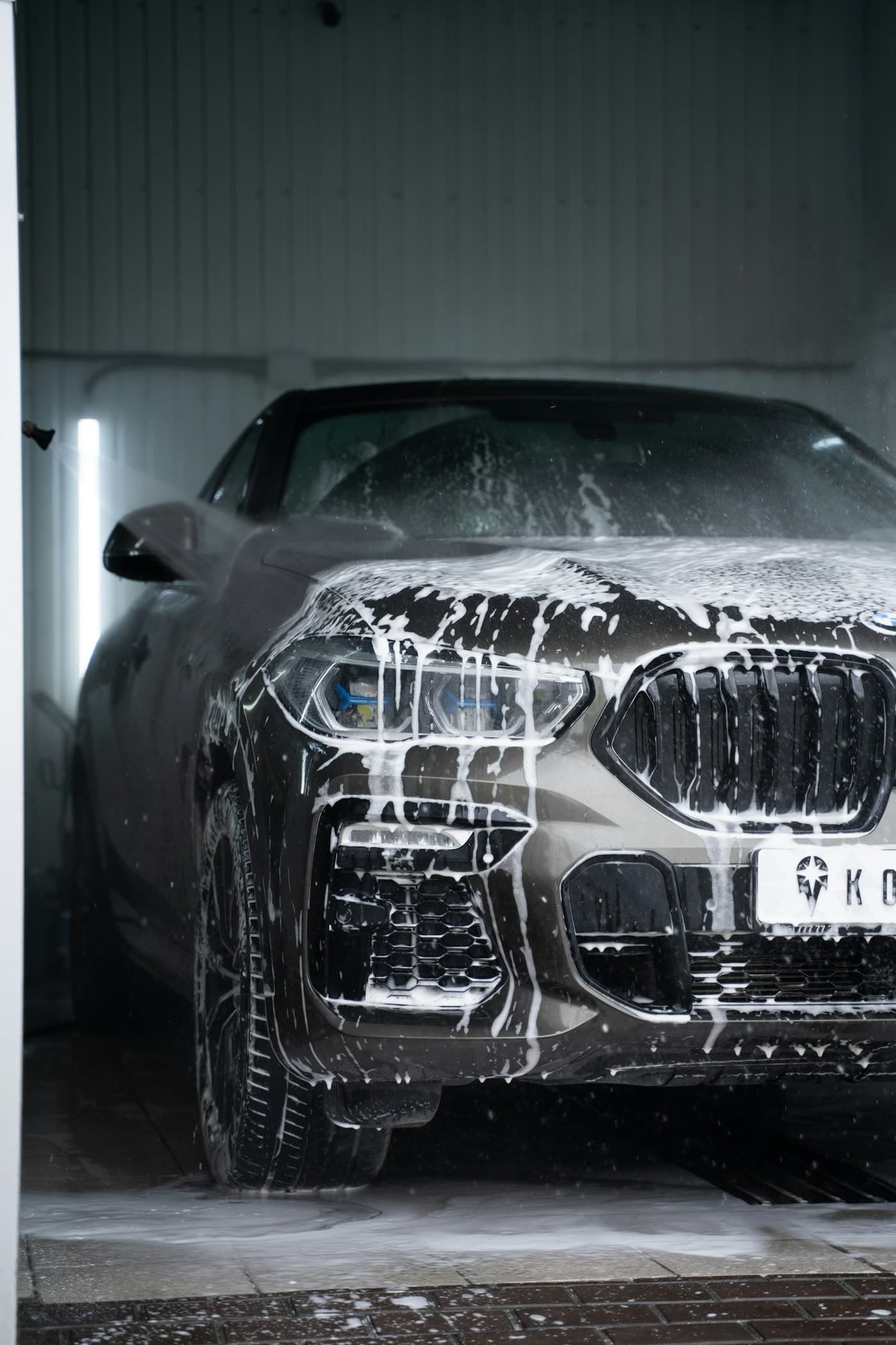 A car covered in white foam during a wash.
