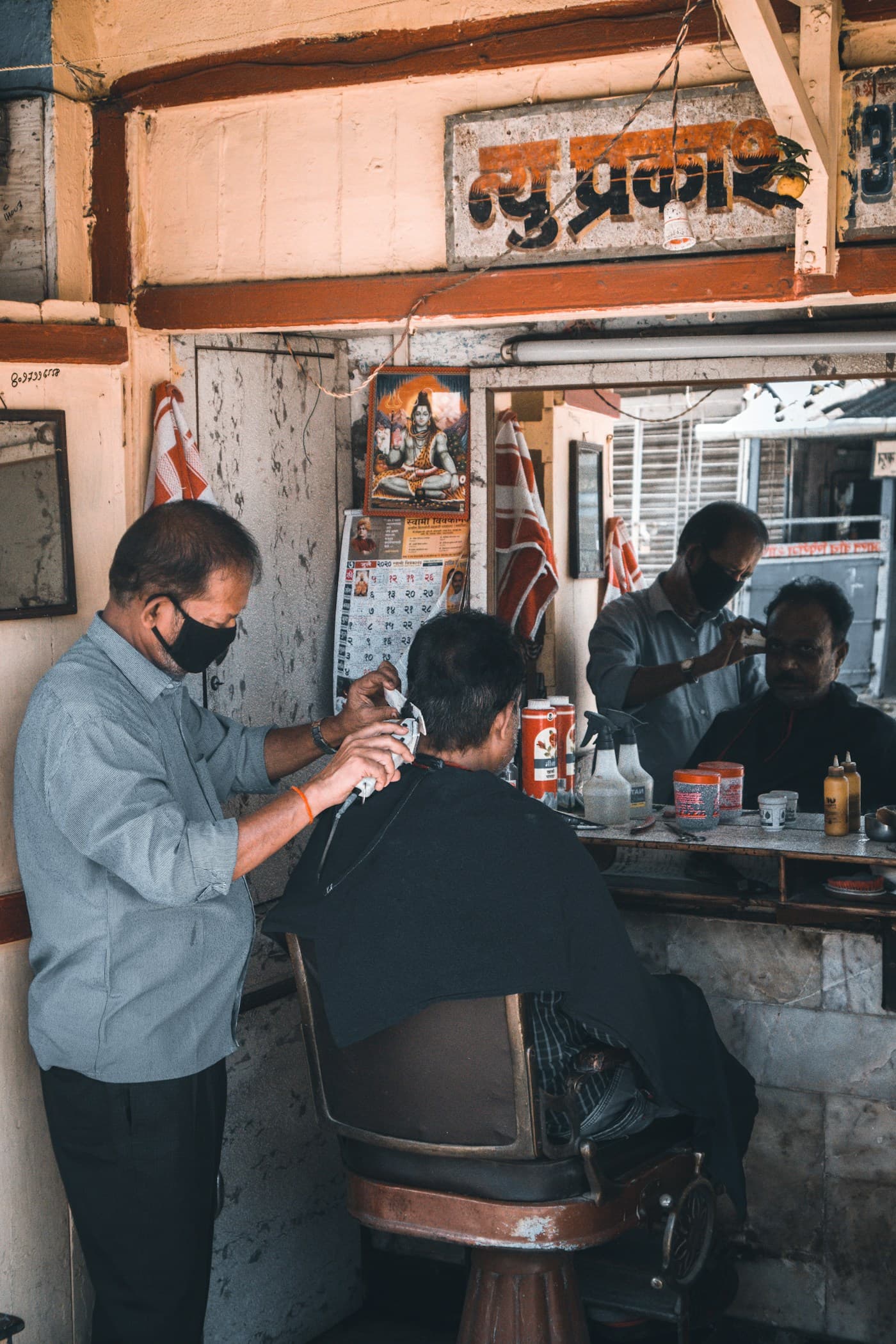 A barber trimming a customer’s hair in a small neighbourhood shop.